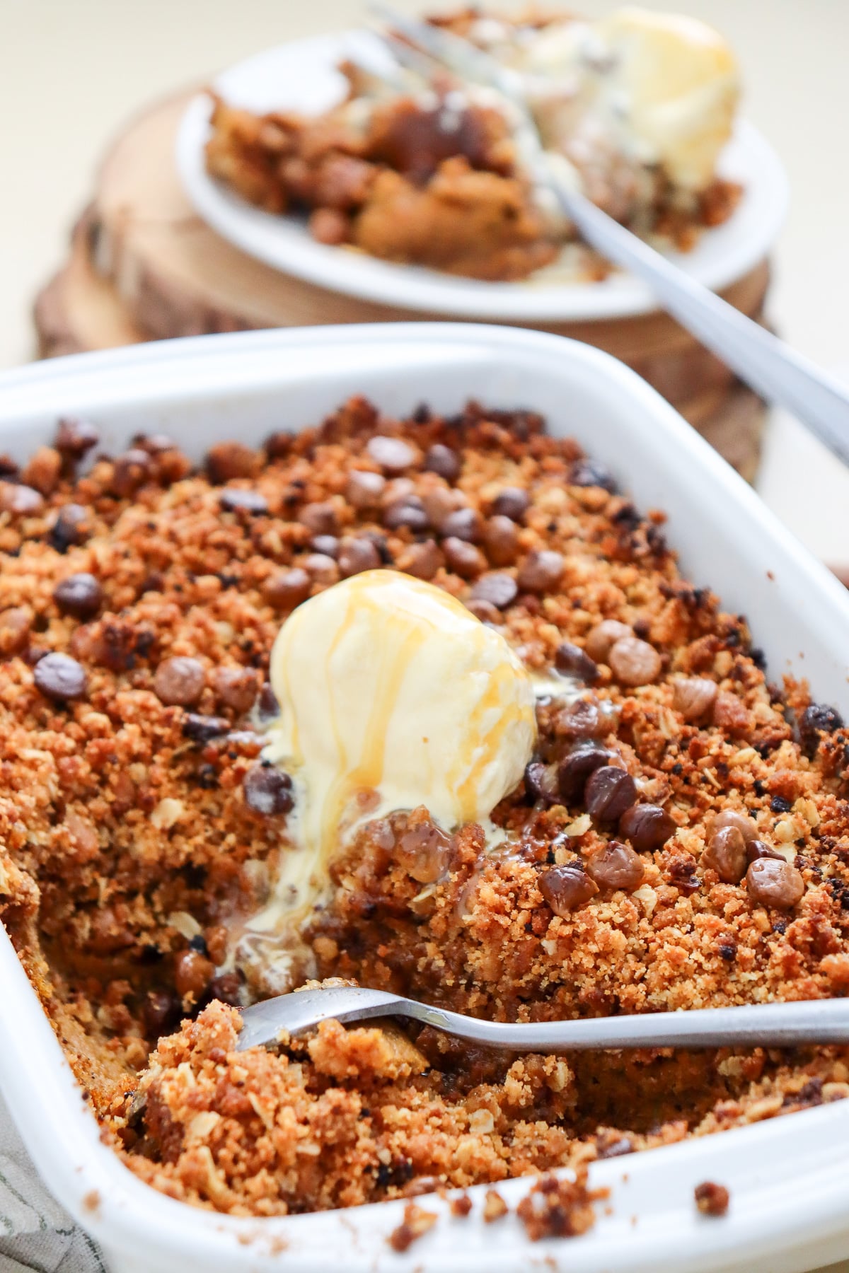Pumpkin crispy with vanilla ice cream in 9x13-inch baking dish.