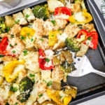 Sheet pan mozzarella chicken on baking sheet with serving spoon.