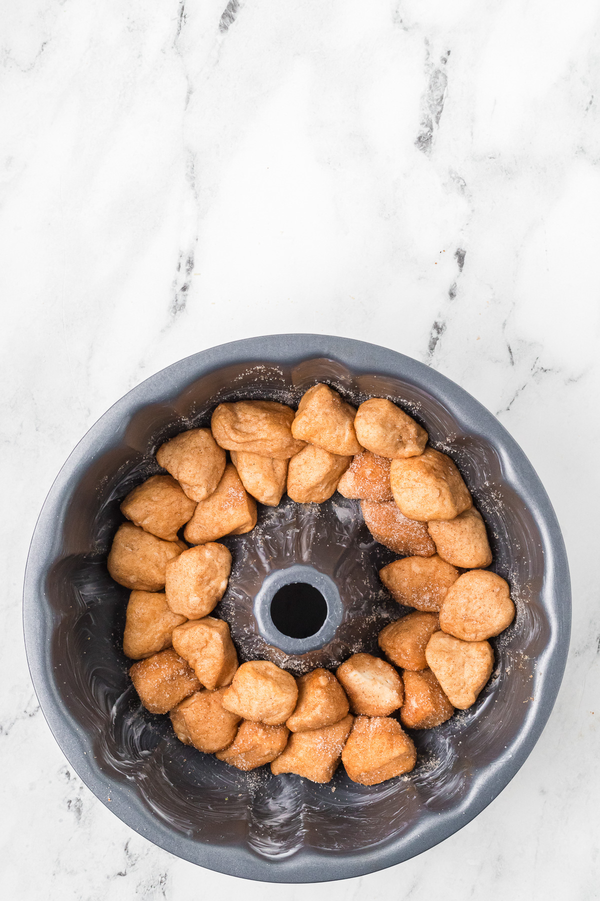 Half of the cinnamon-sugared biscuits placed in bottom of bundt pan.