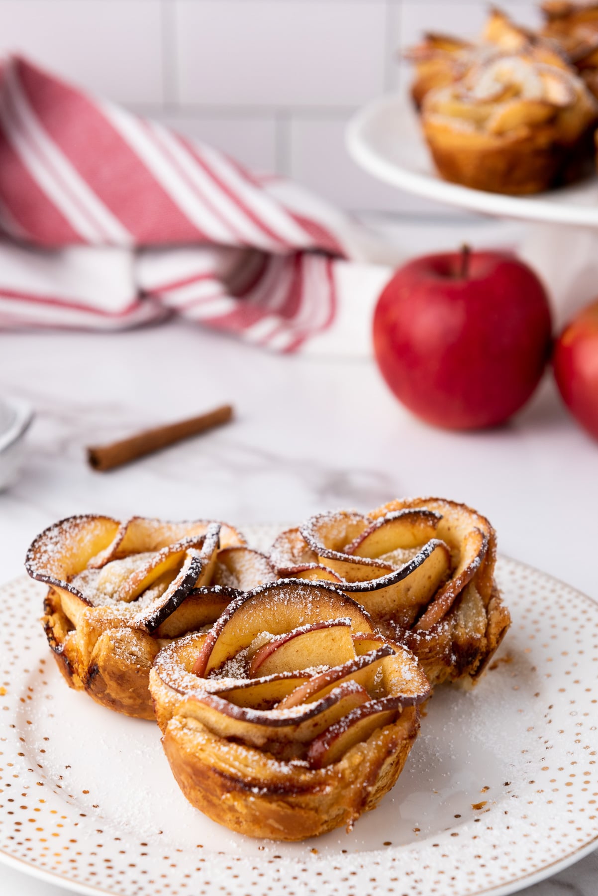 Finished puff pastry apple roses on a white plate.