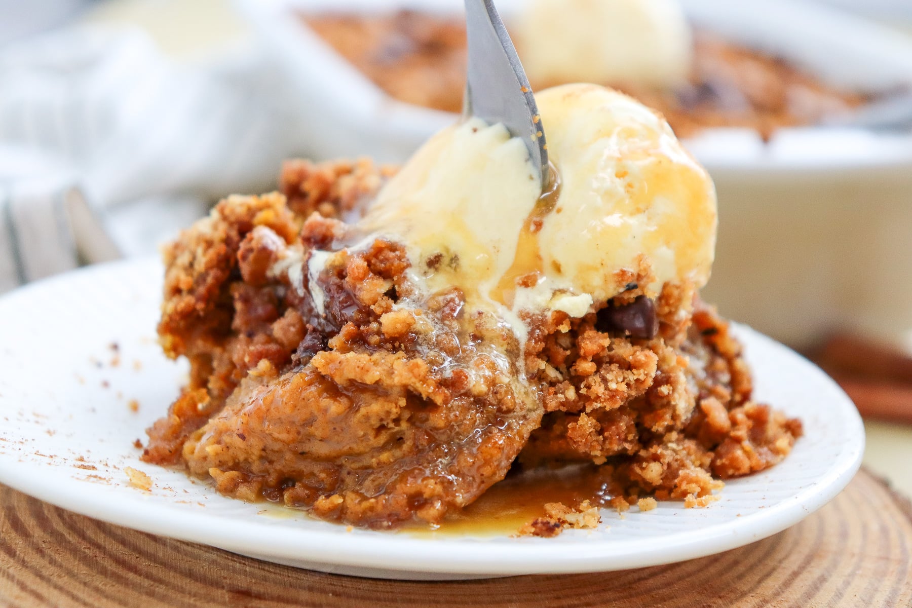Serving of pumpkin crispy with vanilla ice cream on plate.