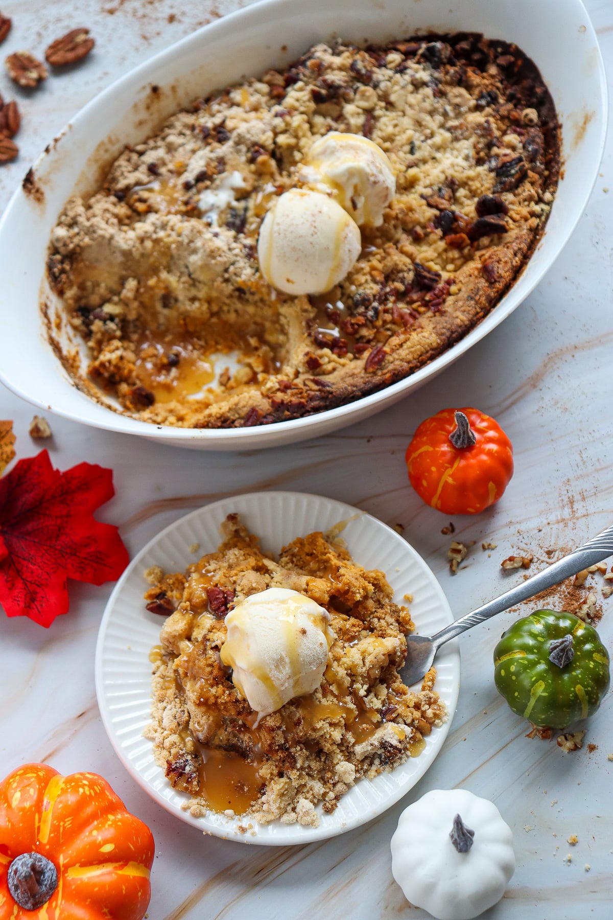 Pumpkin cheesecake dump cake served with vanilla ice cream on a white plate.