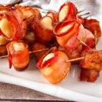 Bacon-wrapped water chesnuts arranged on a serving tray for a holiday party.