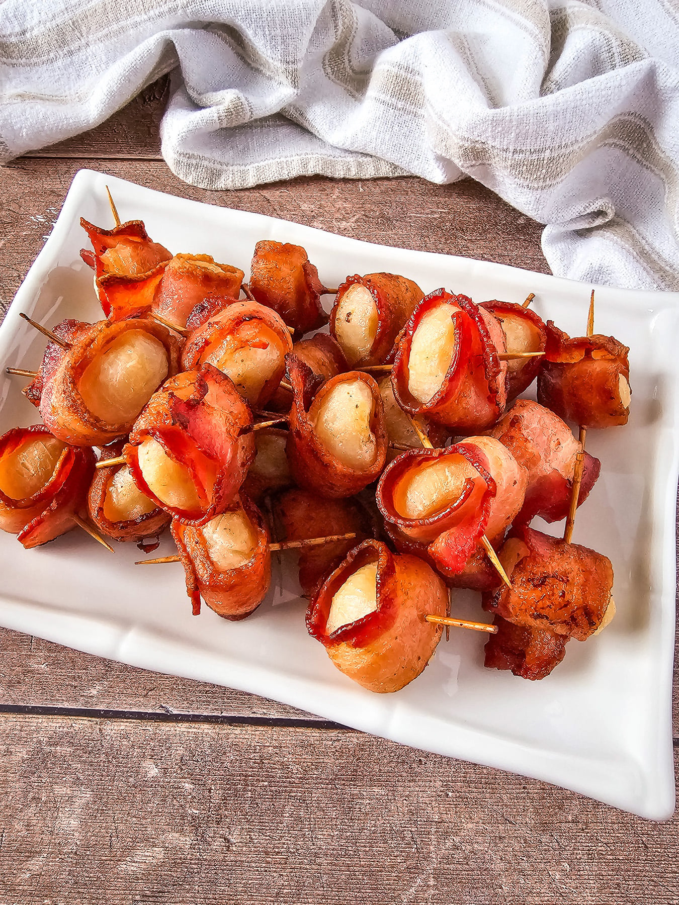 Bacon wrapped appetizers on a white plate.