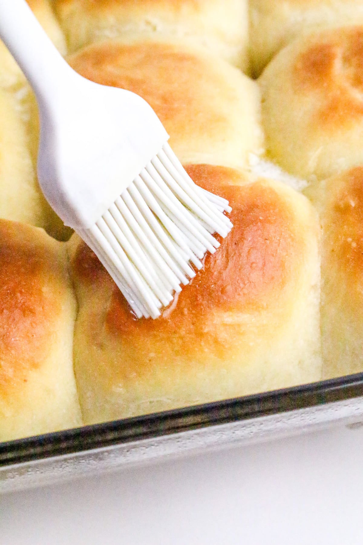 Butter is brushed on dinner rolls after removing them from the oven.