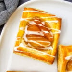 Puff pastry apple danish on a whtie plate.