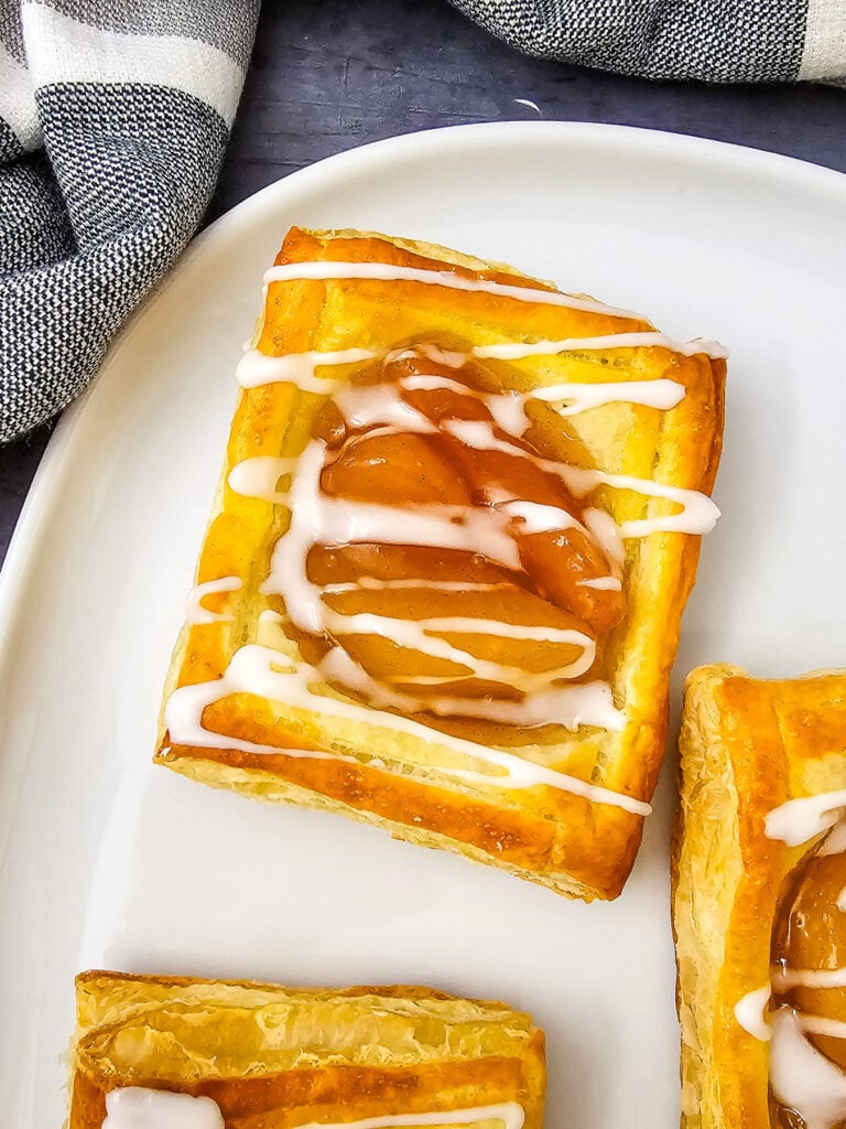 Puff pastry apple danish on a whtie plate.