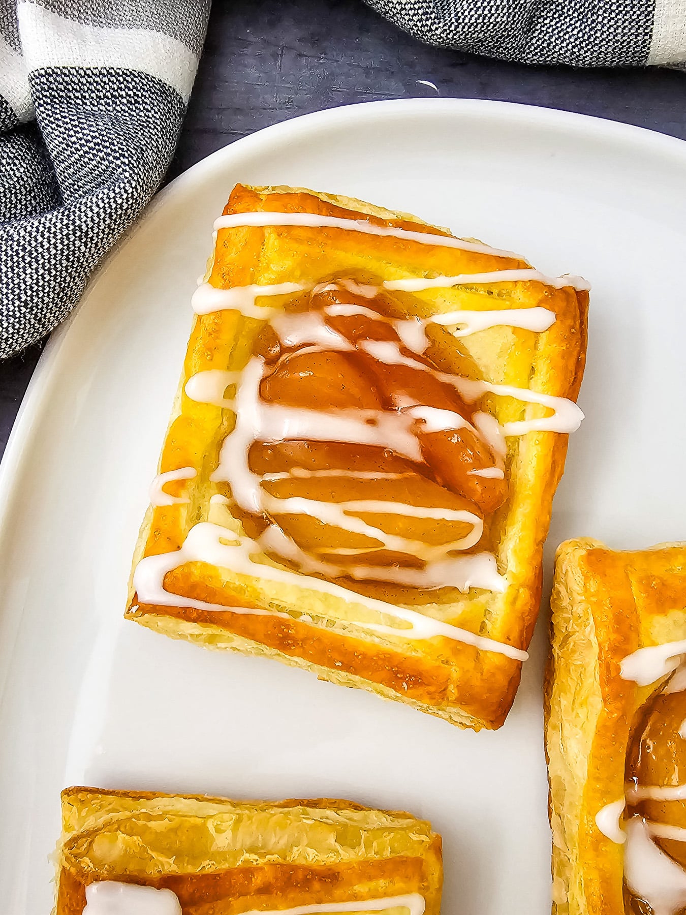 Puff pastry apple danish on a whtie plate.