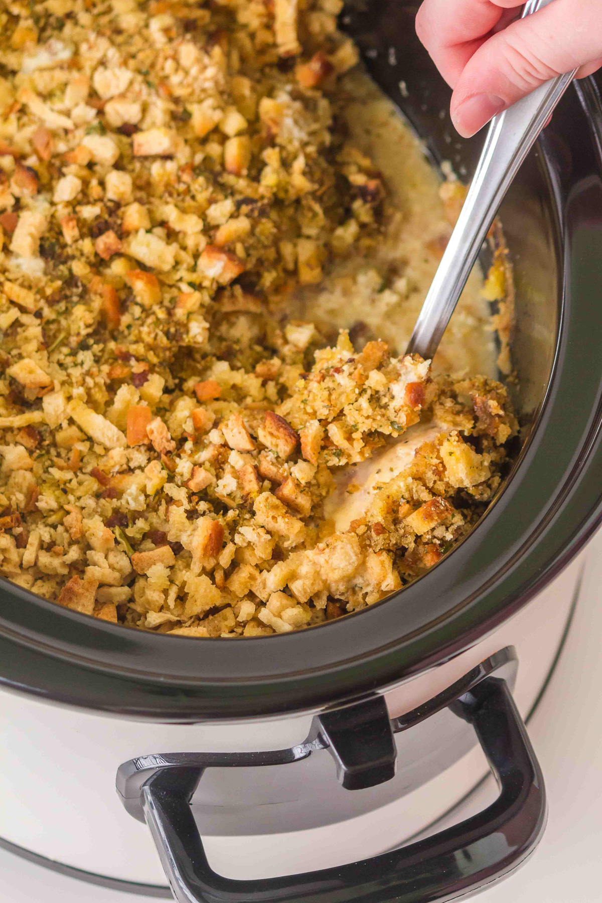 Finished dish in crockpot scooped up in a spoon ready to be served.