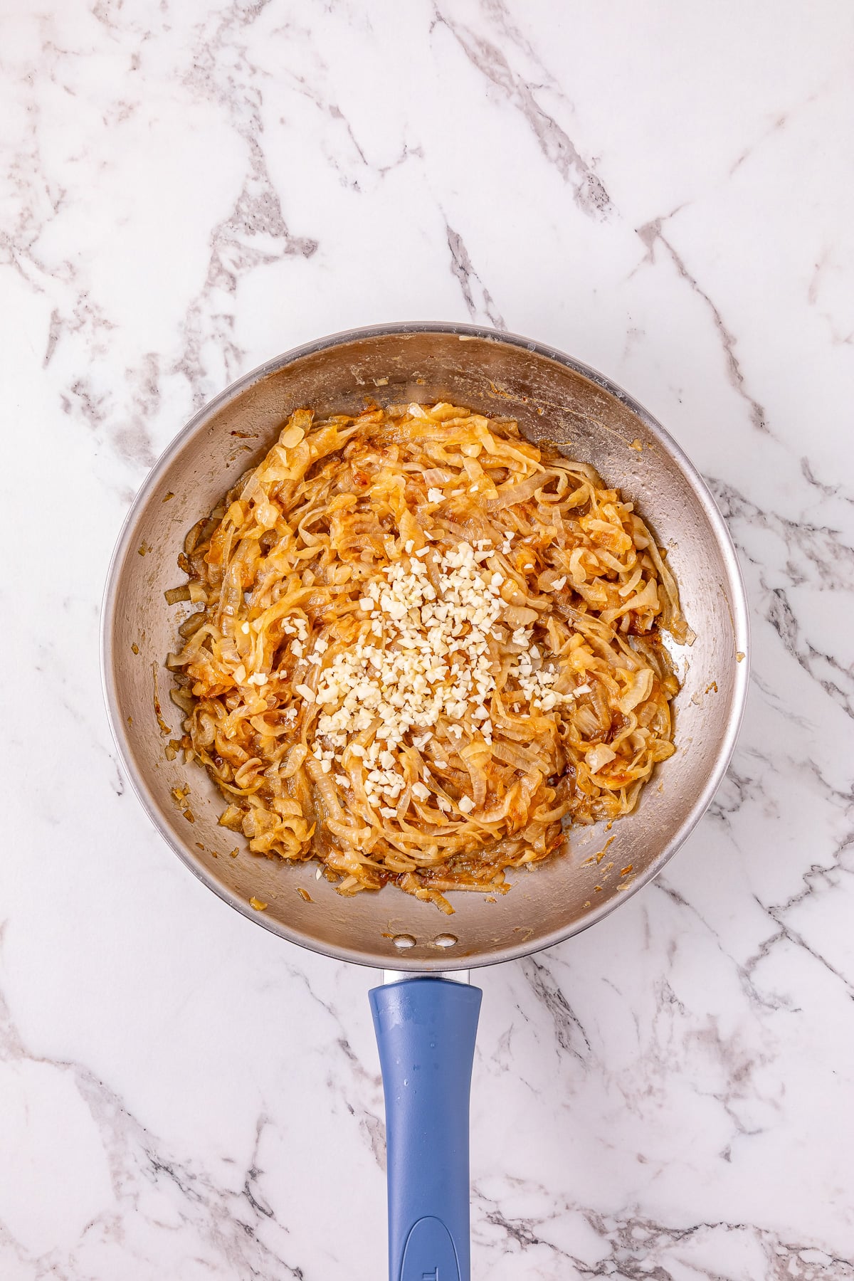 Garlic is added to the caramelized onions in the skillet.