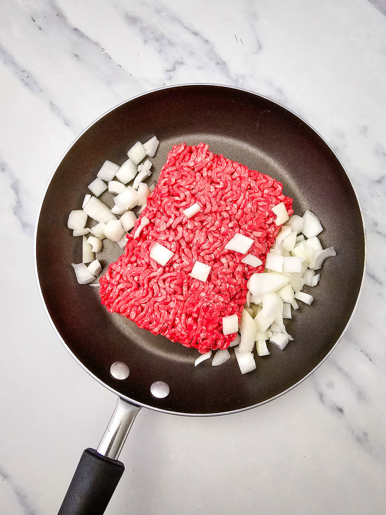 Ground beef and onions in skillet.