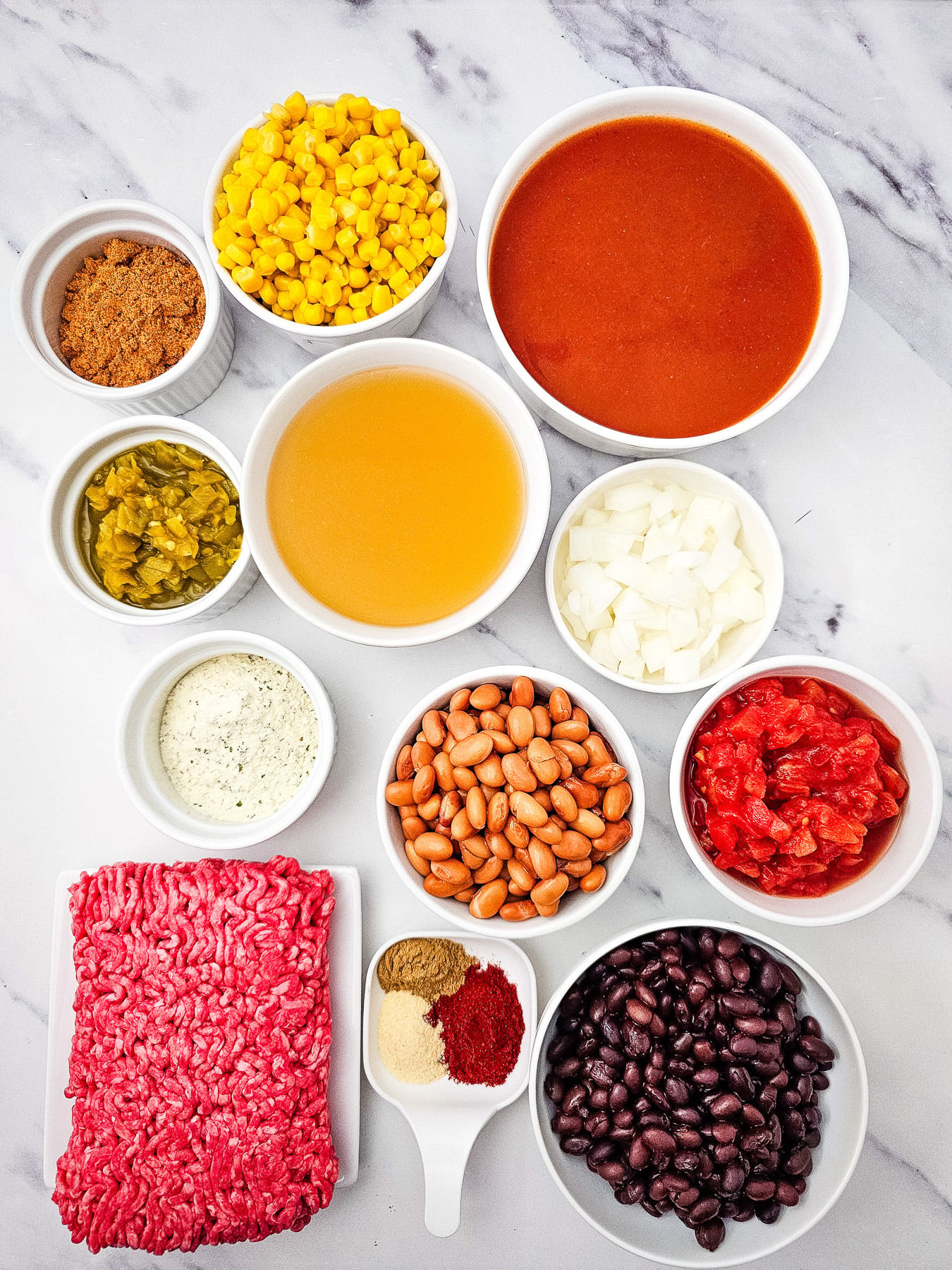 Ingredients for 7 can taco soup in small bowls on counter in prepration for the recipe.