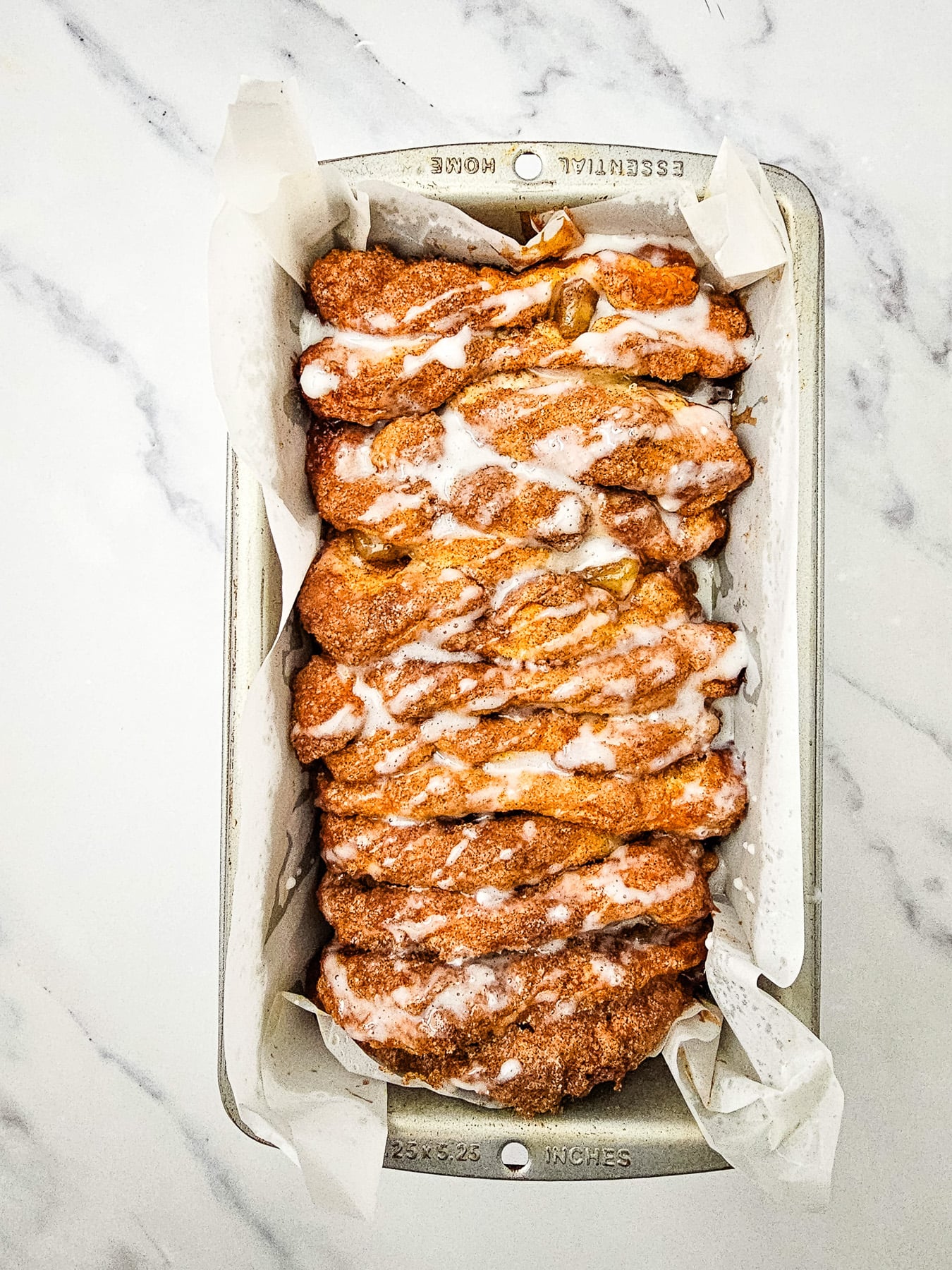 Glaze is drizzled on top of baked apple biscuit loaf.