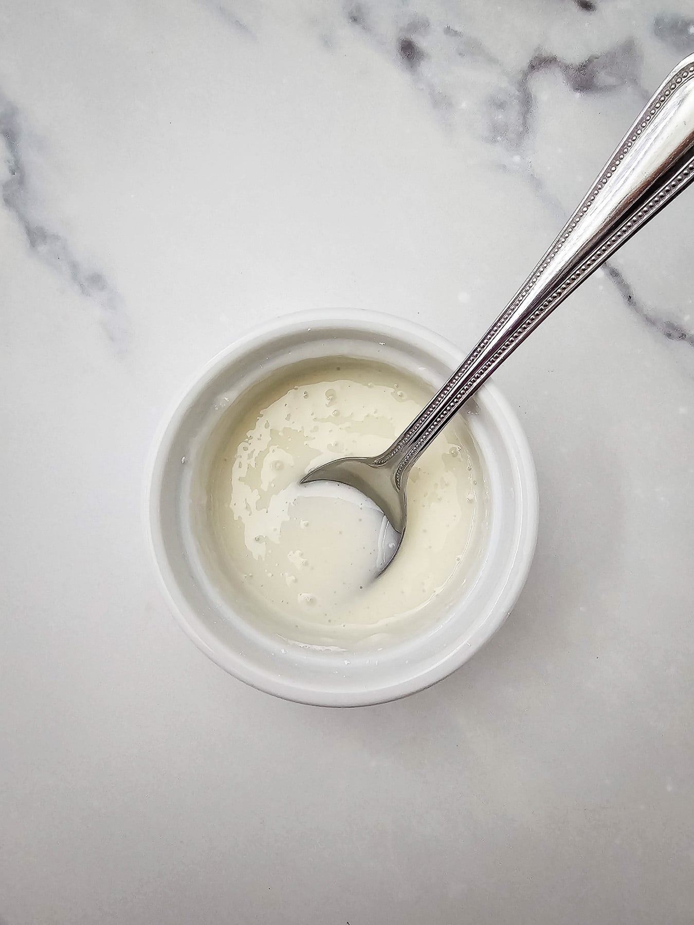 Powdered sugar glaze in small bowl with a spoon.