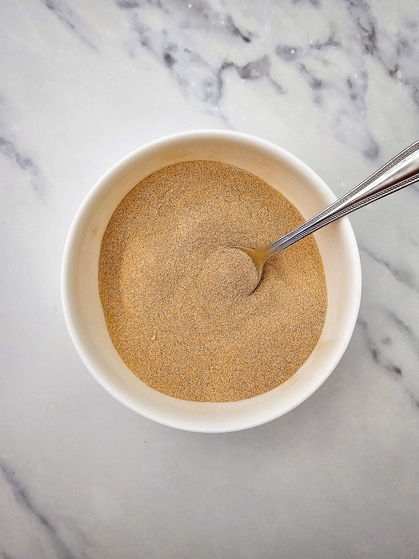 Cinnamon sugar mixture in glass mixing bowl.