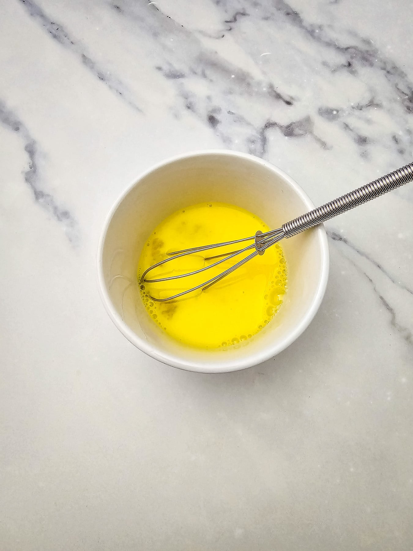 Eggs whisked in mixing bowl.