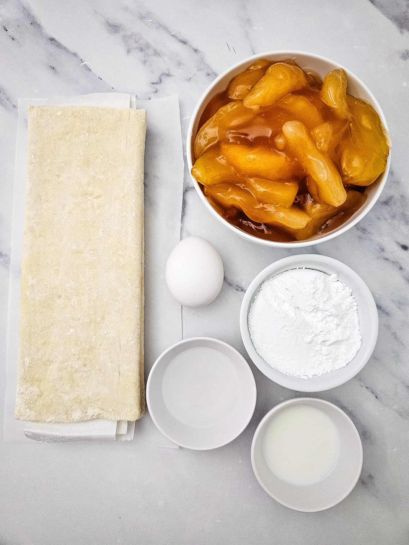 Ingredients for puff pastry apple danish in small bowls on kitchen counter.