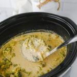 Finished dish of broccoli cheddar soup scooped up with ladle.