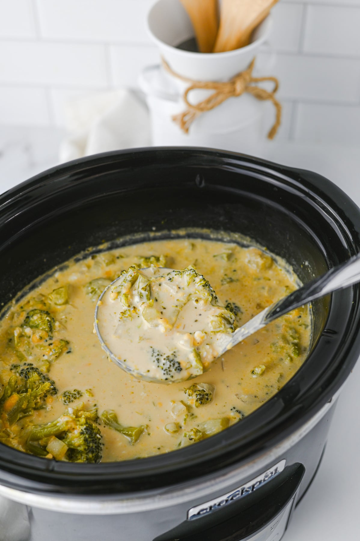 Finished dish of broccoli cheddar soup scooped up with ladle.