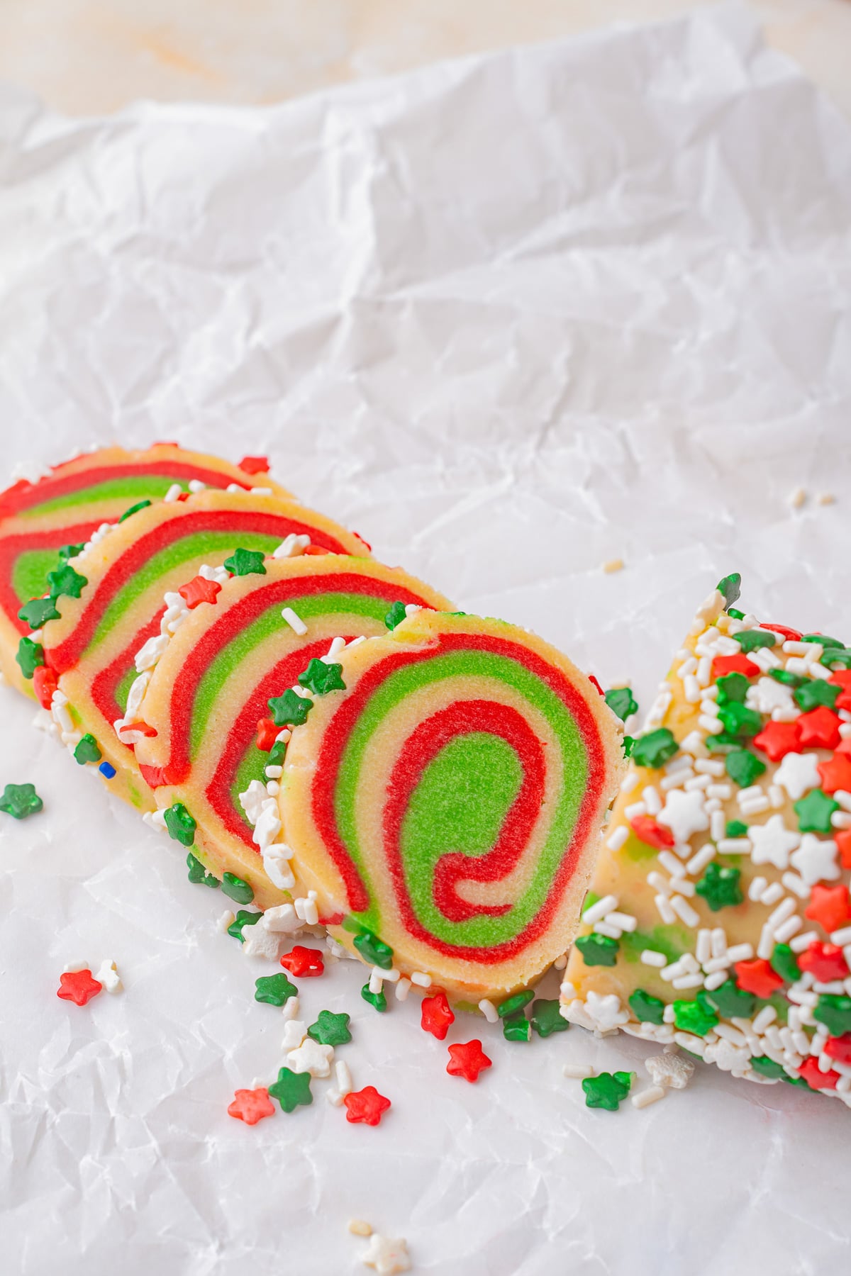 Sliced unbaked cookies on parchment lined baking dish.