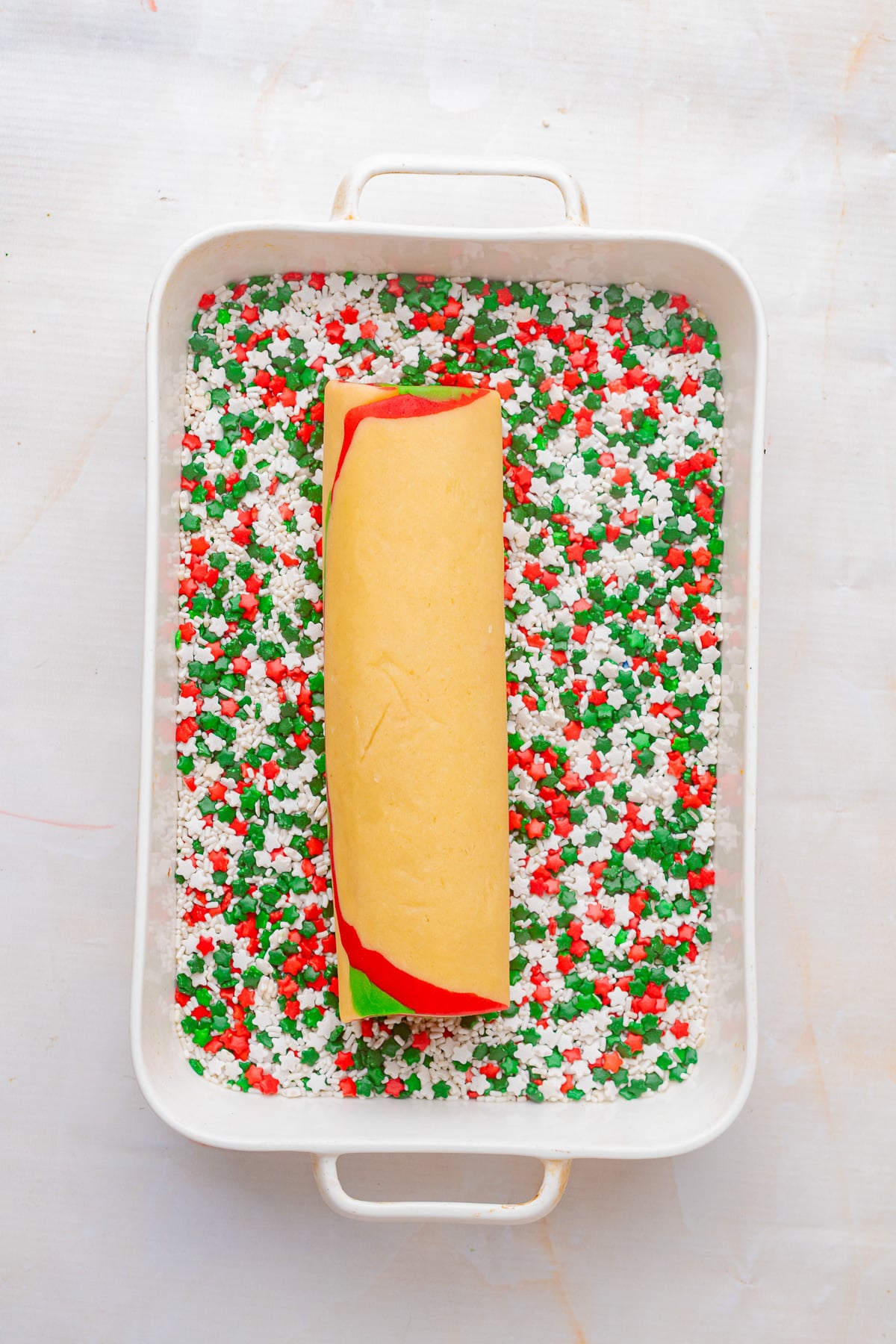 With sprinkles in bottom of baking sheet, the dough is rolled on top.