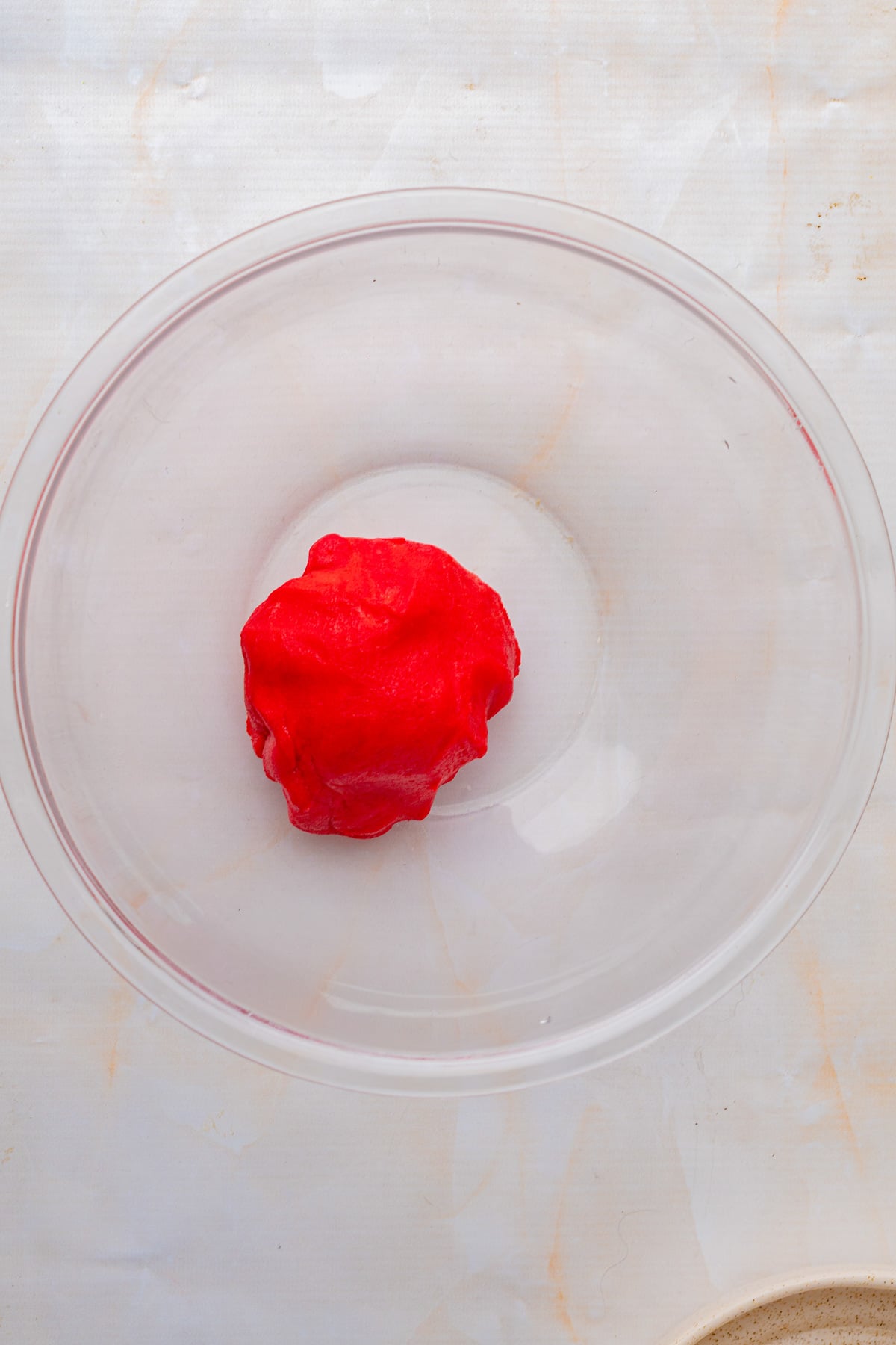 Red cookie dough ball in glass bowl.
