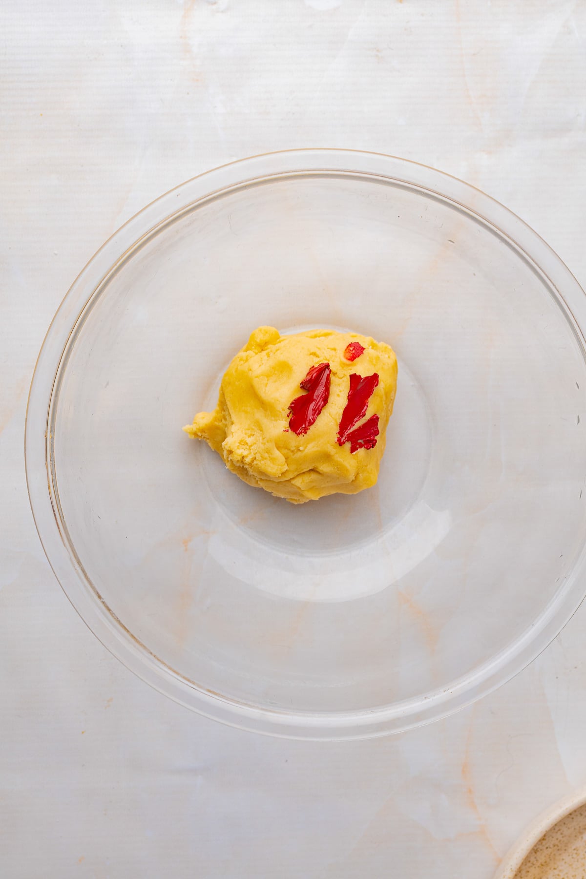 Red gel food coloring is added to one of the cookie dough balls.