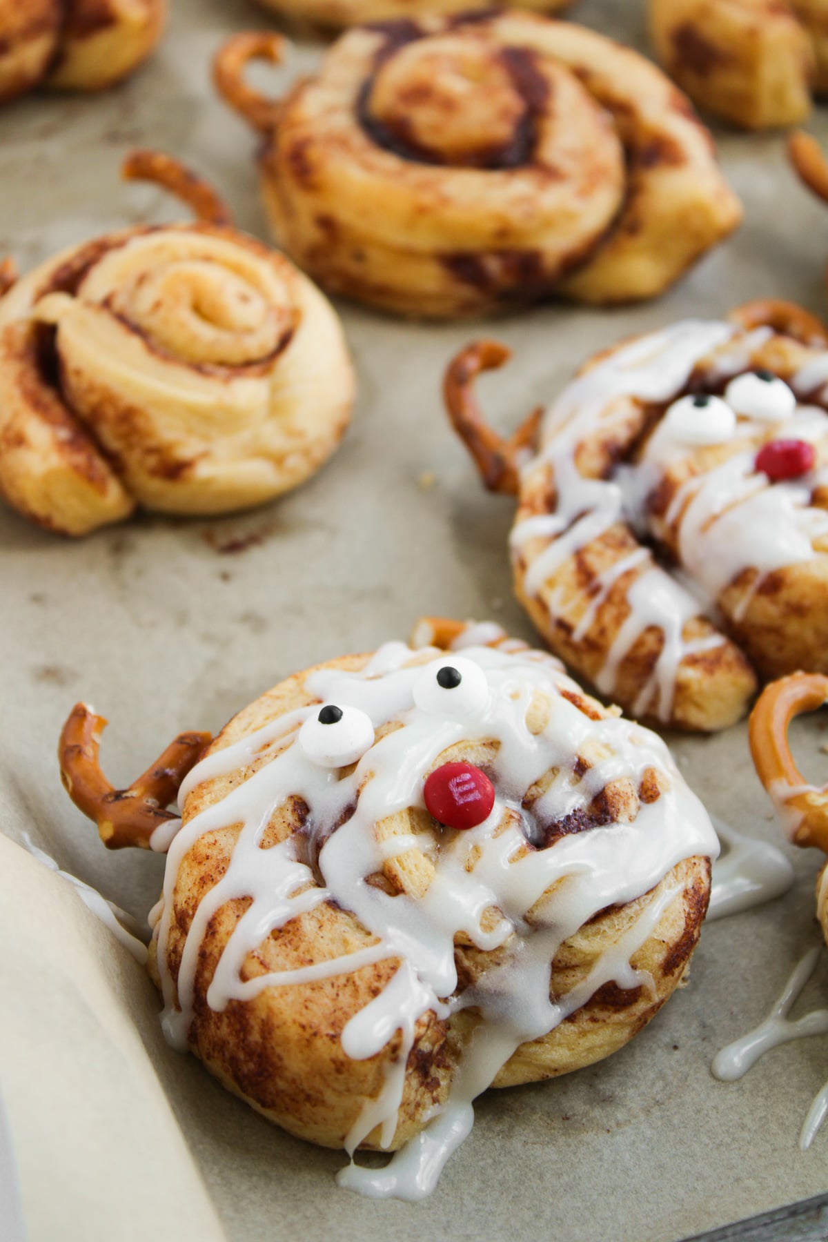 Reindeer cinnamon rolls on parchment lined baking sheet.