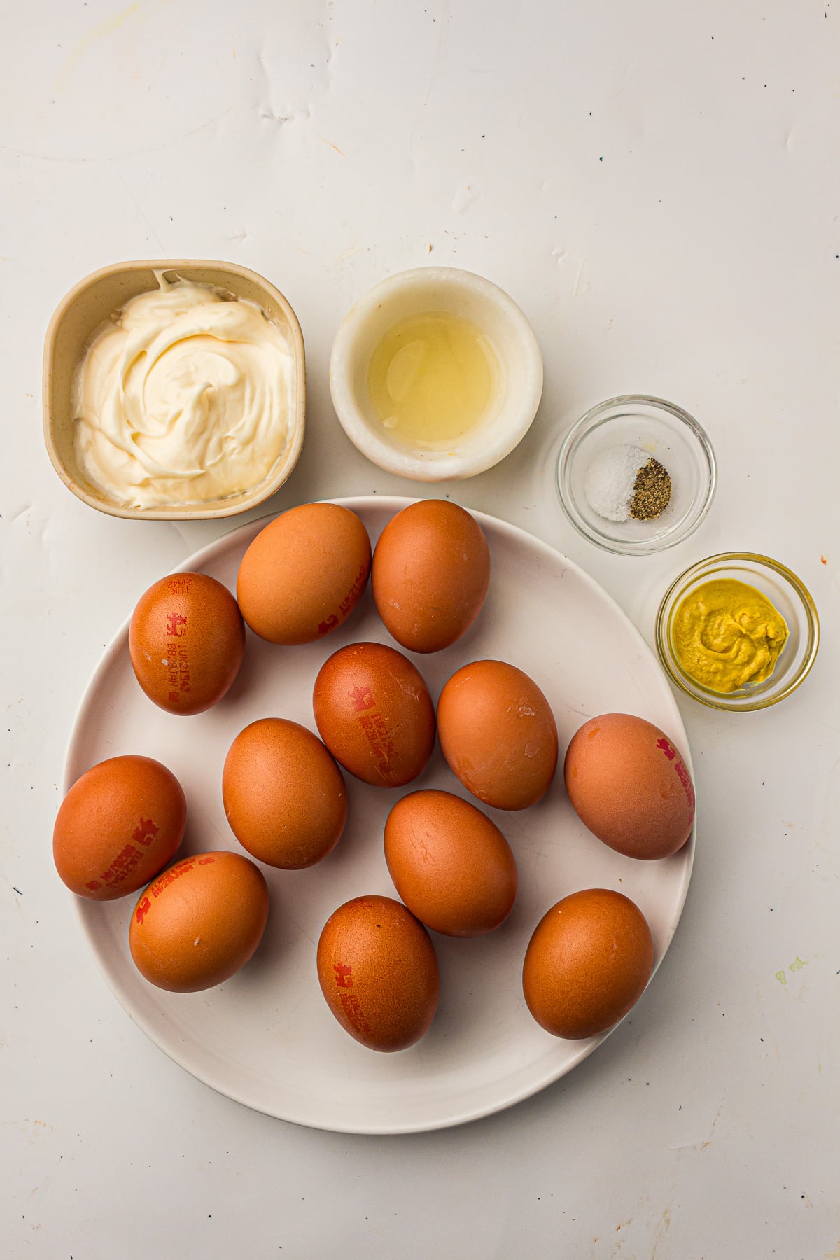 Ingredients for devilled eggs in small bowls on kitchen counter.