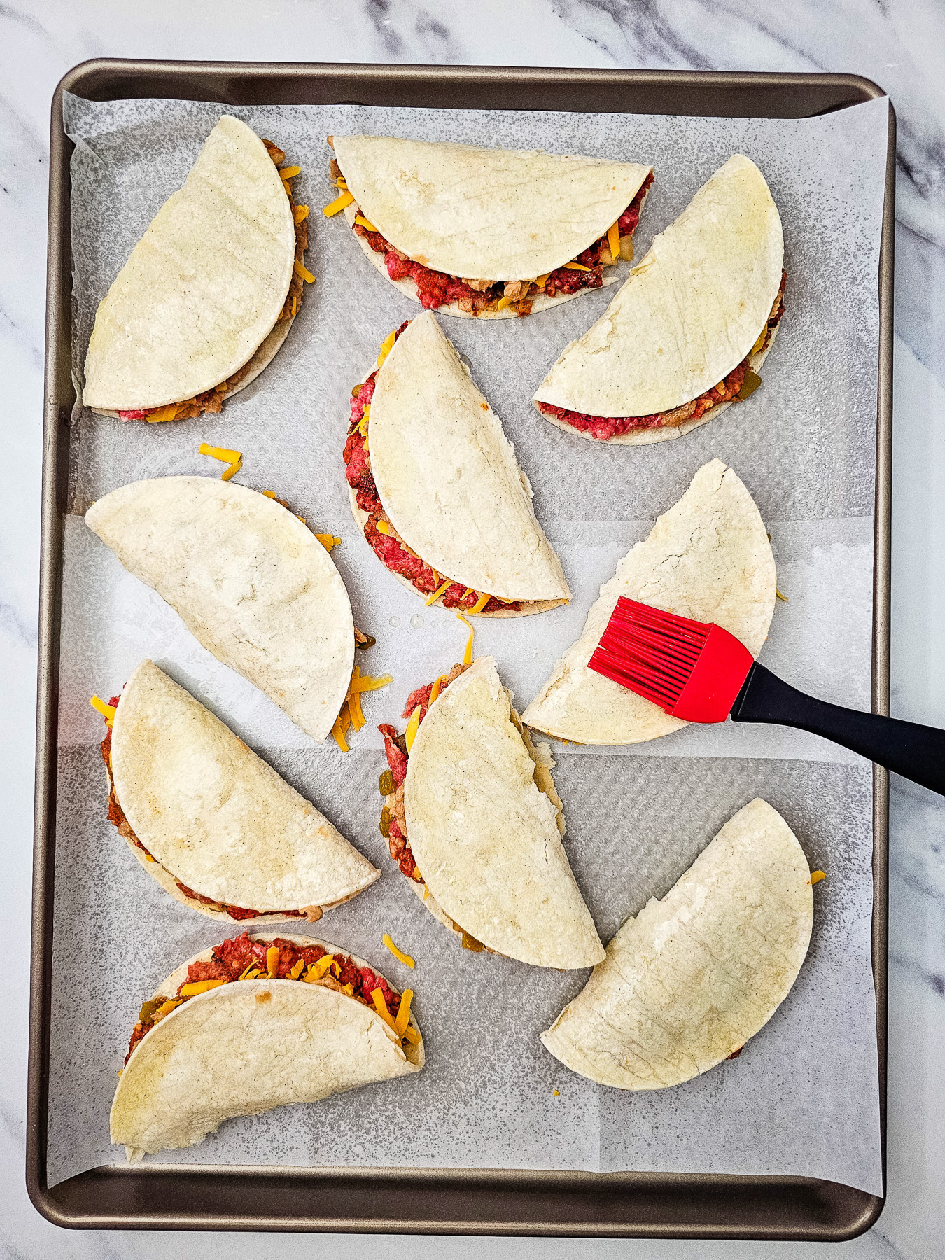 Tops of the folded tacos are brushed with olive oil.