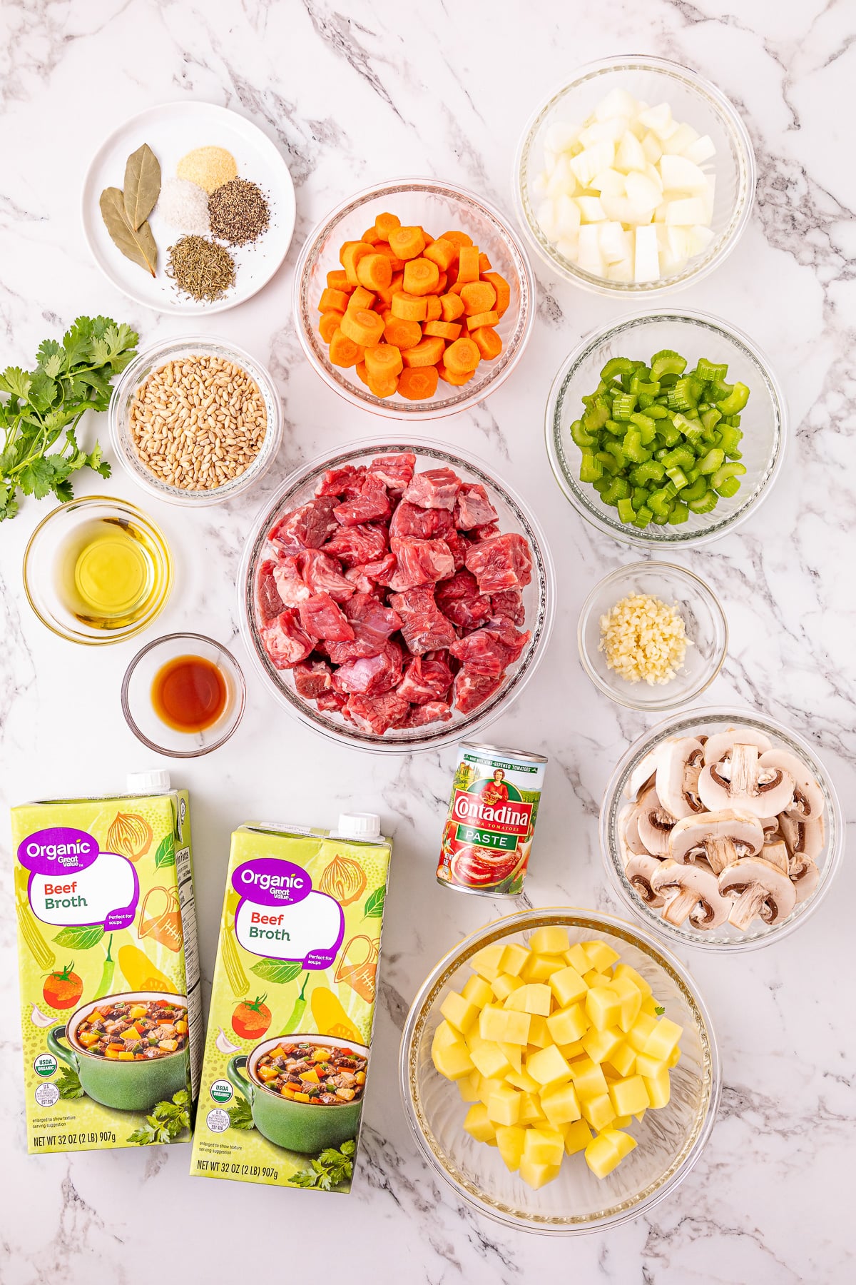 Ingredients for homemade beef barley soup in small bowls on counter.