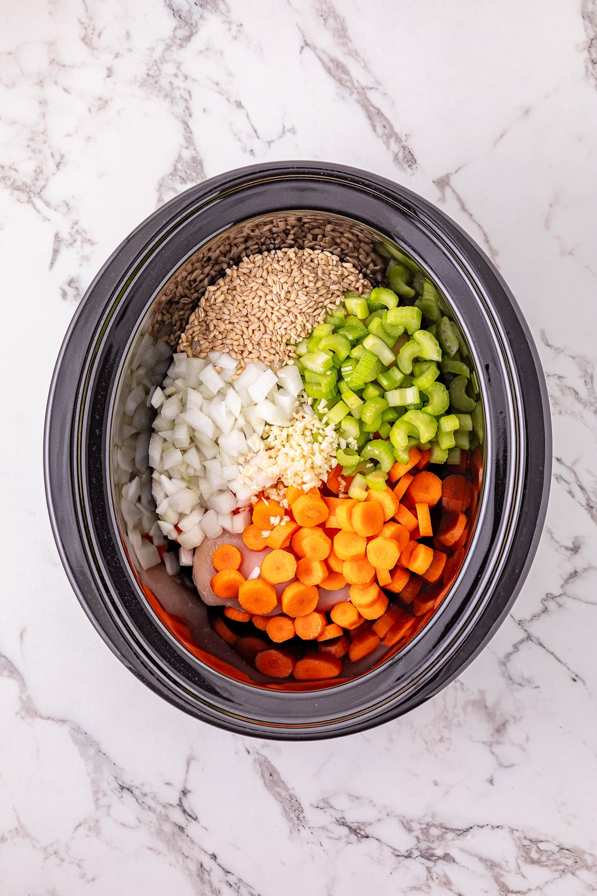 Remaining ingredients are added to the top of the chicken in slow cooker.