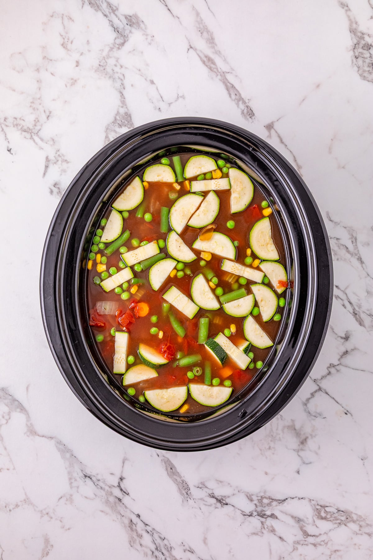 Thawed corn, peas and green beans along with the chopped zucchini are added to the crockpot.