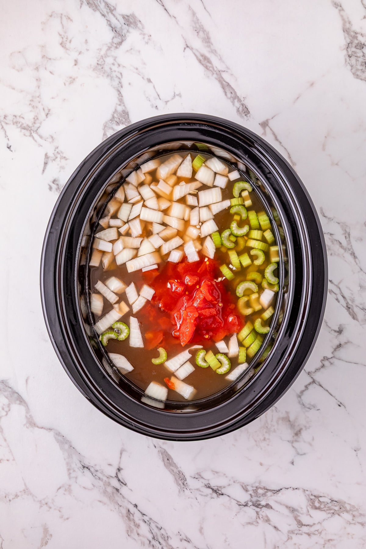 Broth and diced tomatoes are added to the slow cooker.