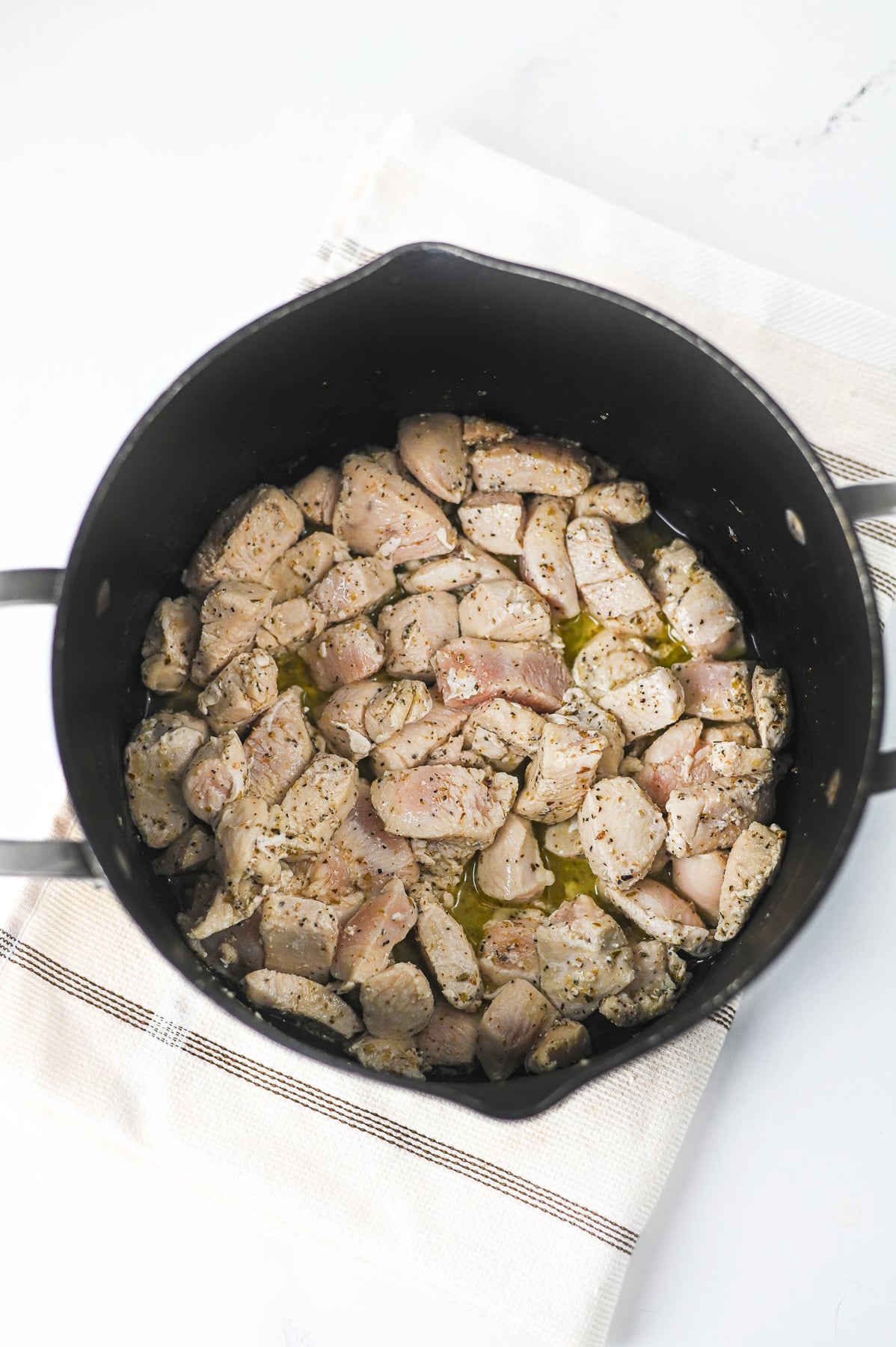 Chicken cooking in bottom of pot.