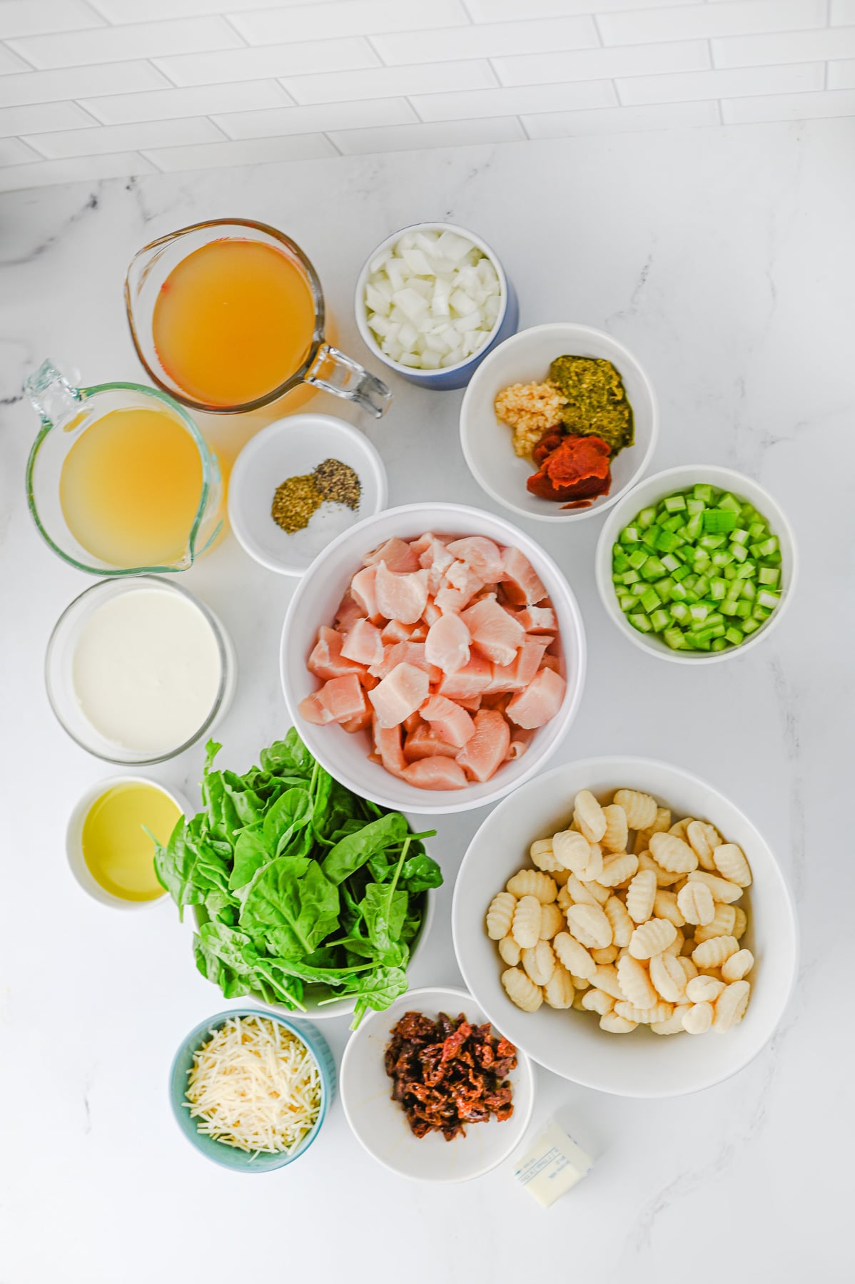 Ingredients for cozy chicken soup in small bowls on kitchen counter.