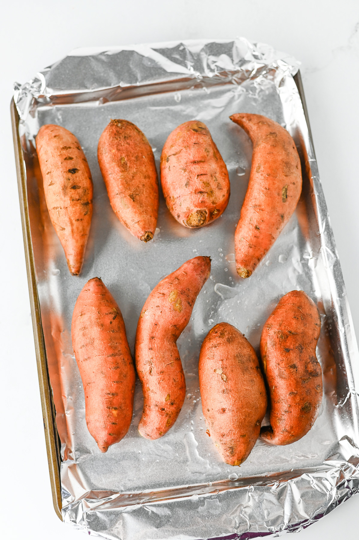Baked potatoes on foil-lined baking sheet.