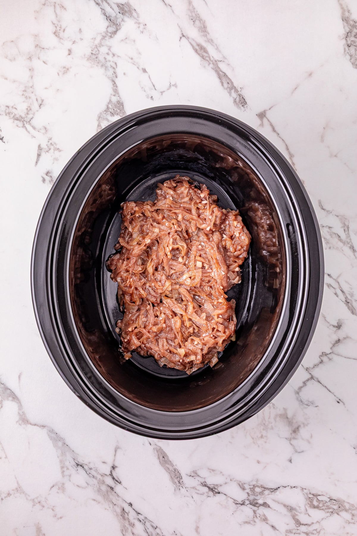 Onion mixture is placed into the bottom of the slow cooker.