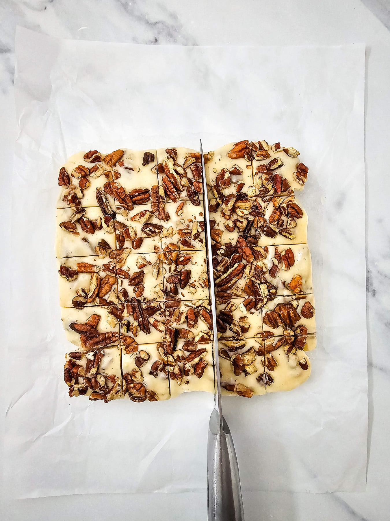 Chilled fudge is cutting on marble slab.