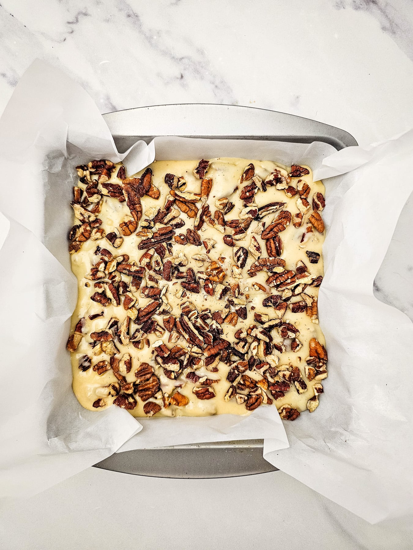 Pecans are sprinkled on top of mixture in pan.