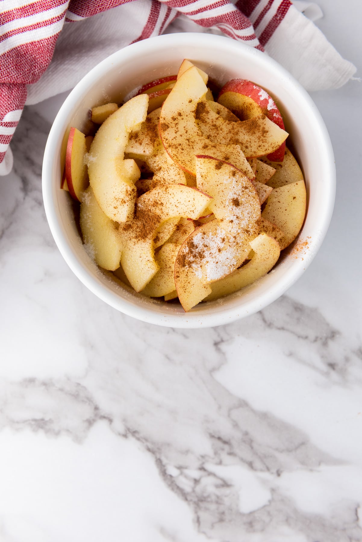 Apple and cinnamon in mixing bowl.