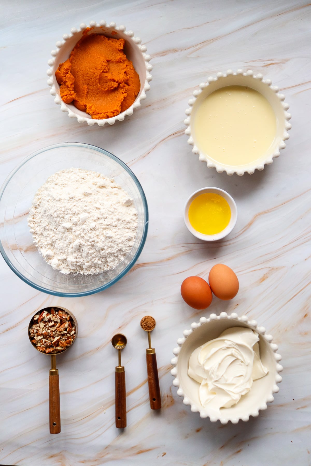 Ingredients for pumpkin dump cake in small bowls on counter.