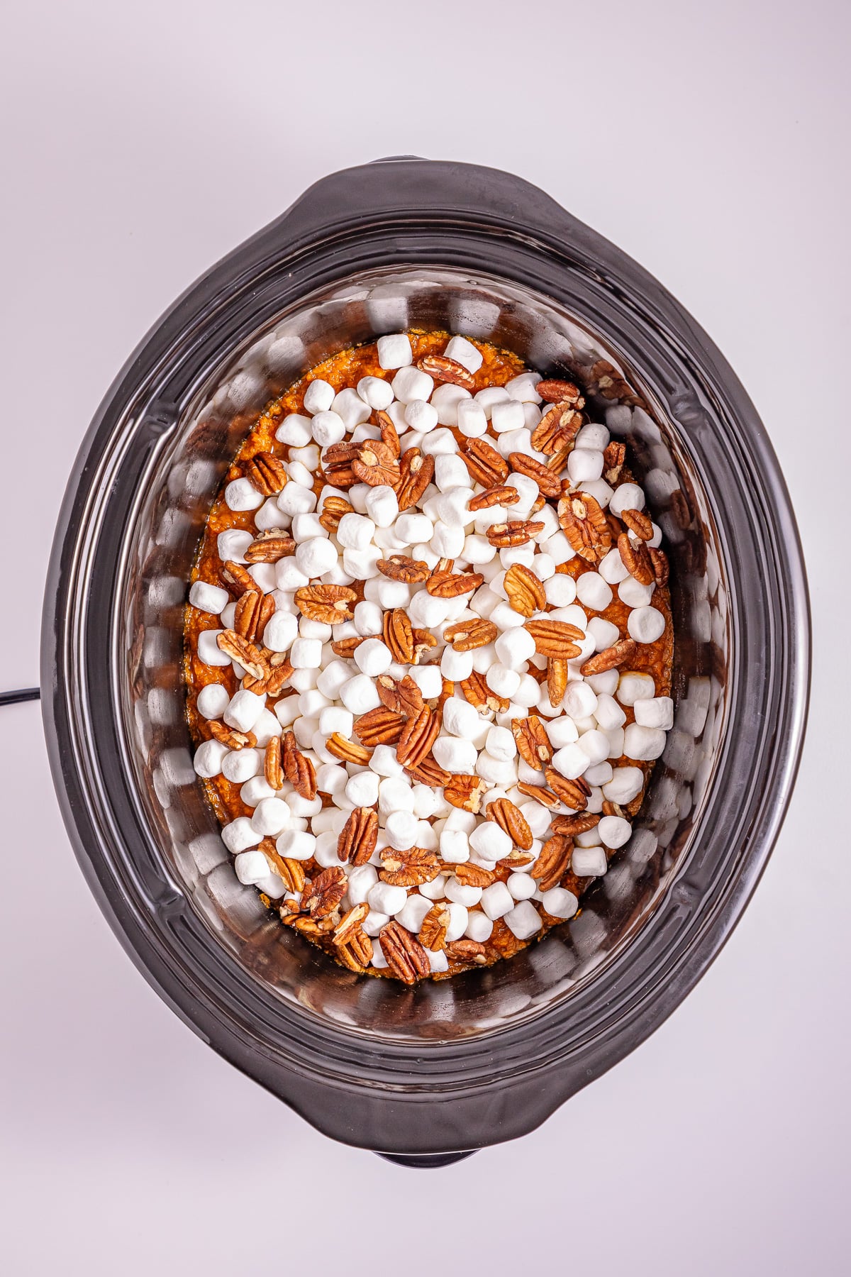 Marshmallows and pecans are sprinkled on top of the mashed sweet potatoes.