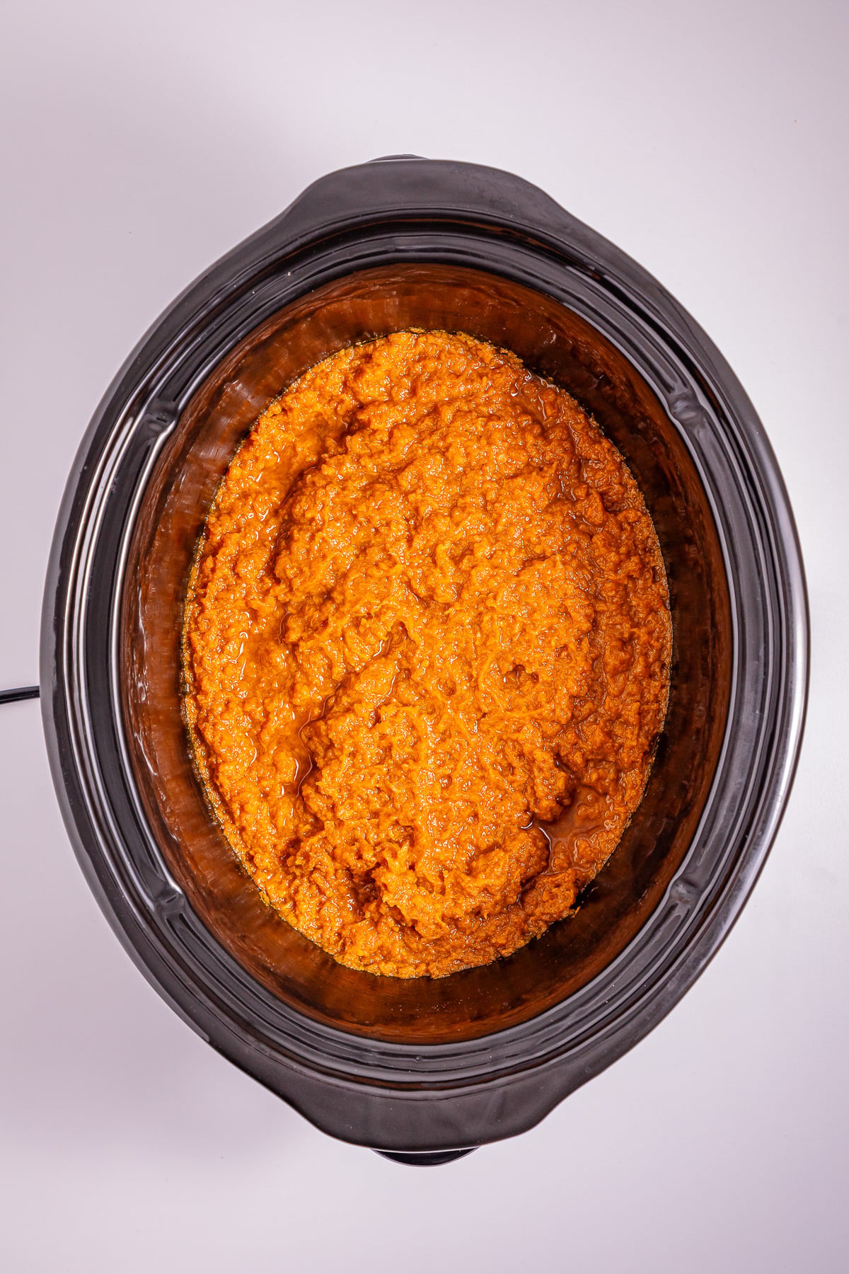 Mashed sweet potatoes in bottom of the slow cooker.