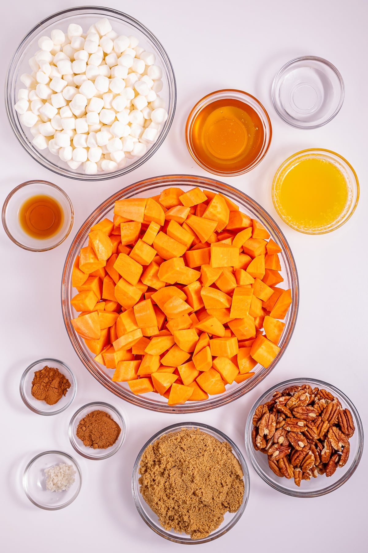 Ingredients for crockpot sweet potato casserole with marshmallow topping laid out in small bowls on kitchen counter.