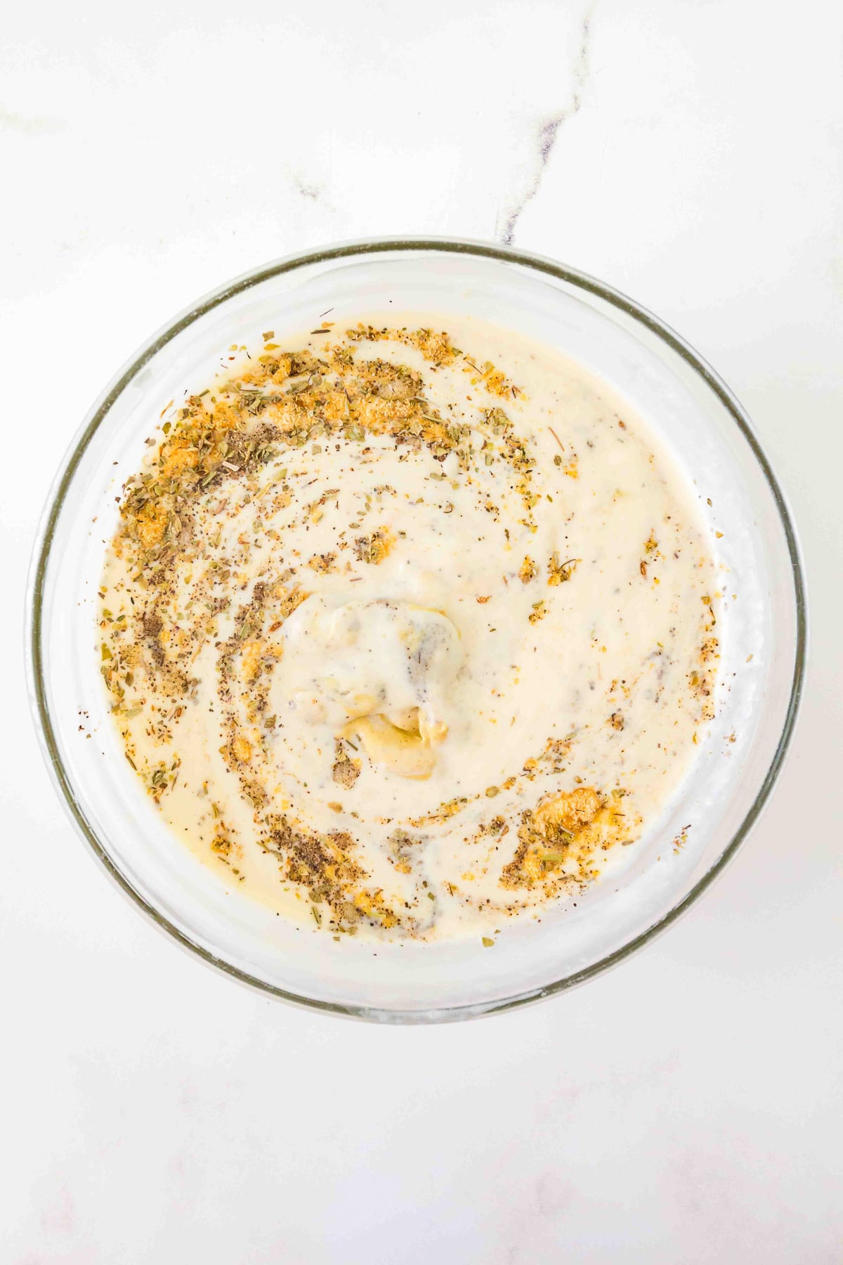 Ingredients for creamy sauce in glass mixing bowl.