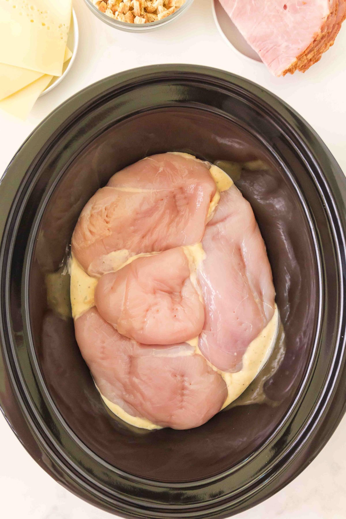 Chicken is layered on top of the sauce in bottom of slow cooker.