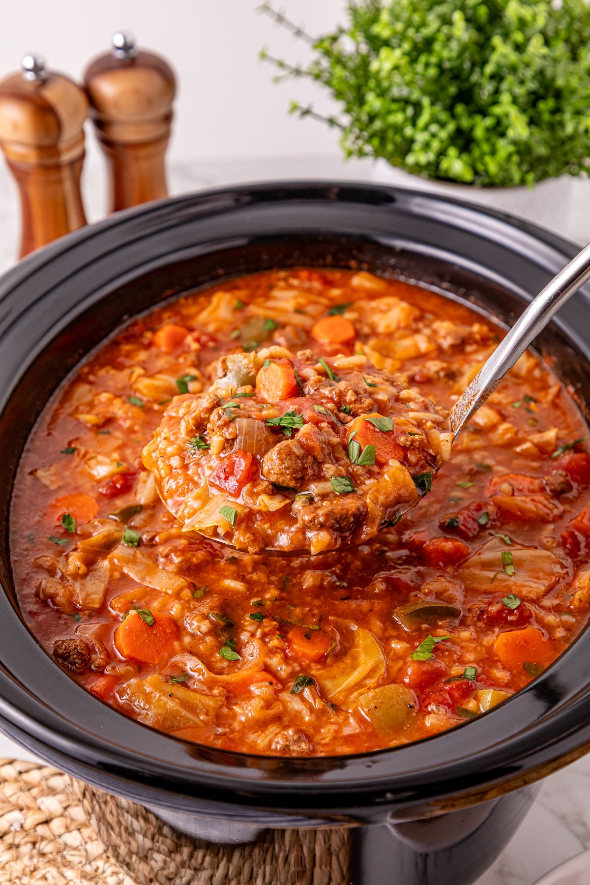 Crockpot cabbage roll soup scooped up in a ladle held over slow cooker.