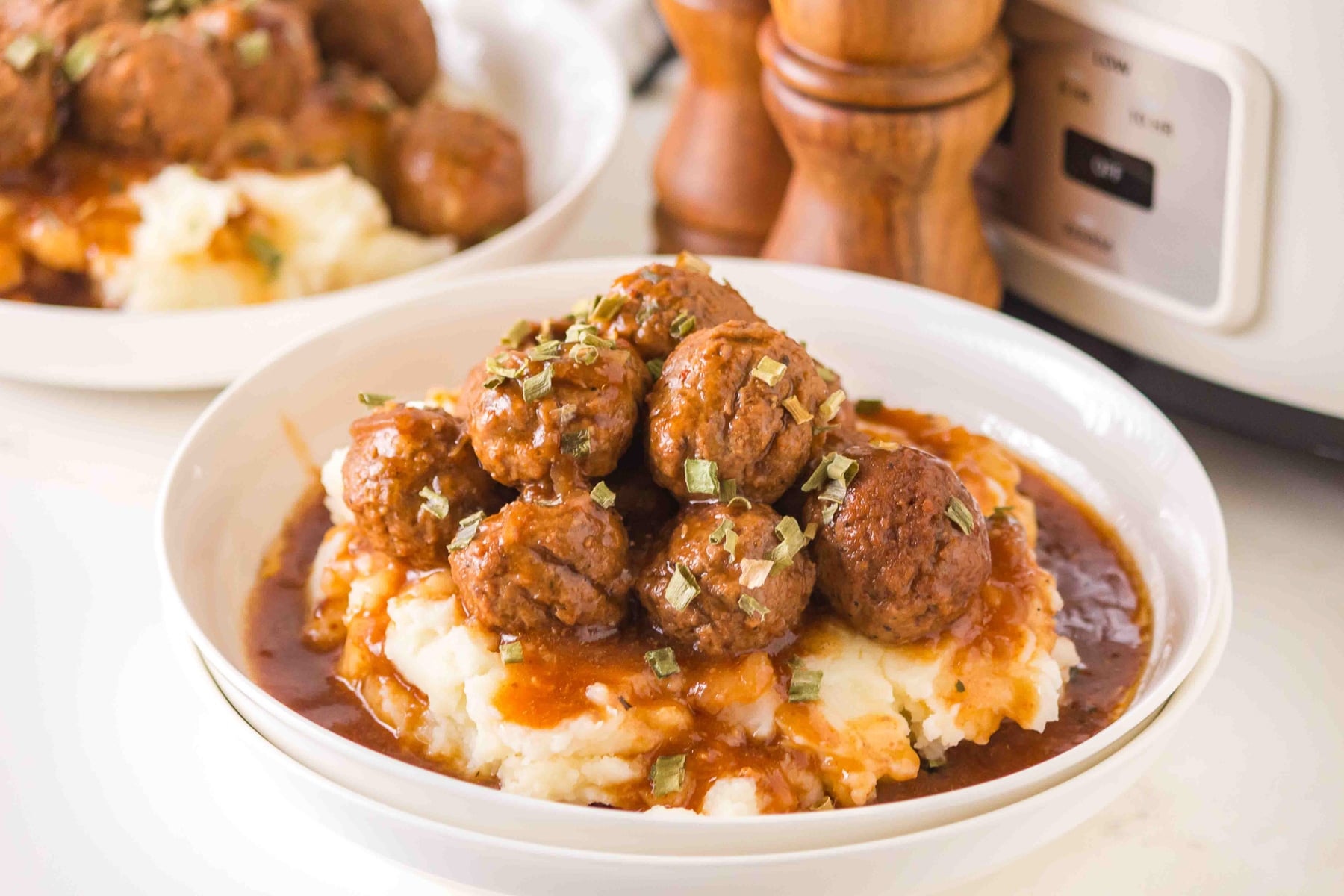 Salisbury meatballs with mashed potatoes and gravy in a white bowl.