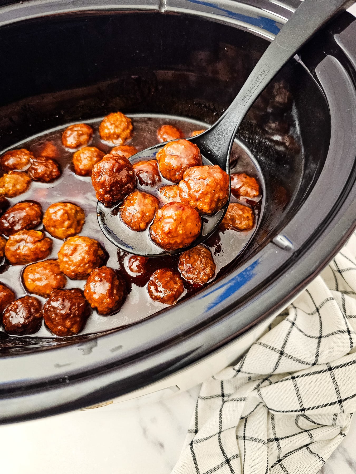 Crockpot grape jelly bbq meatballs in slow cooker scooped up with a spoon.
